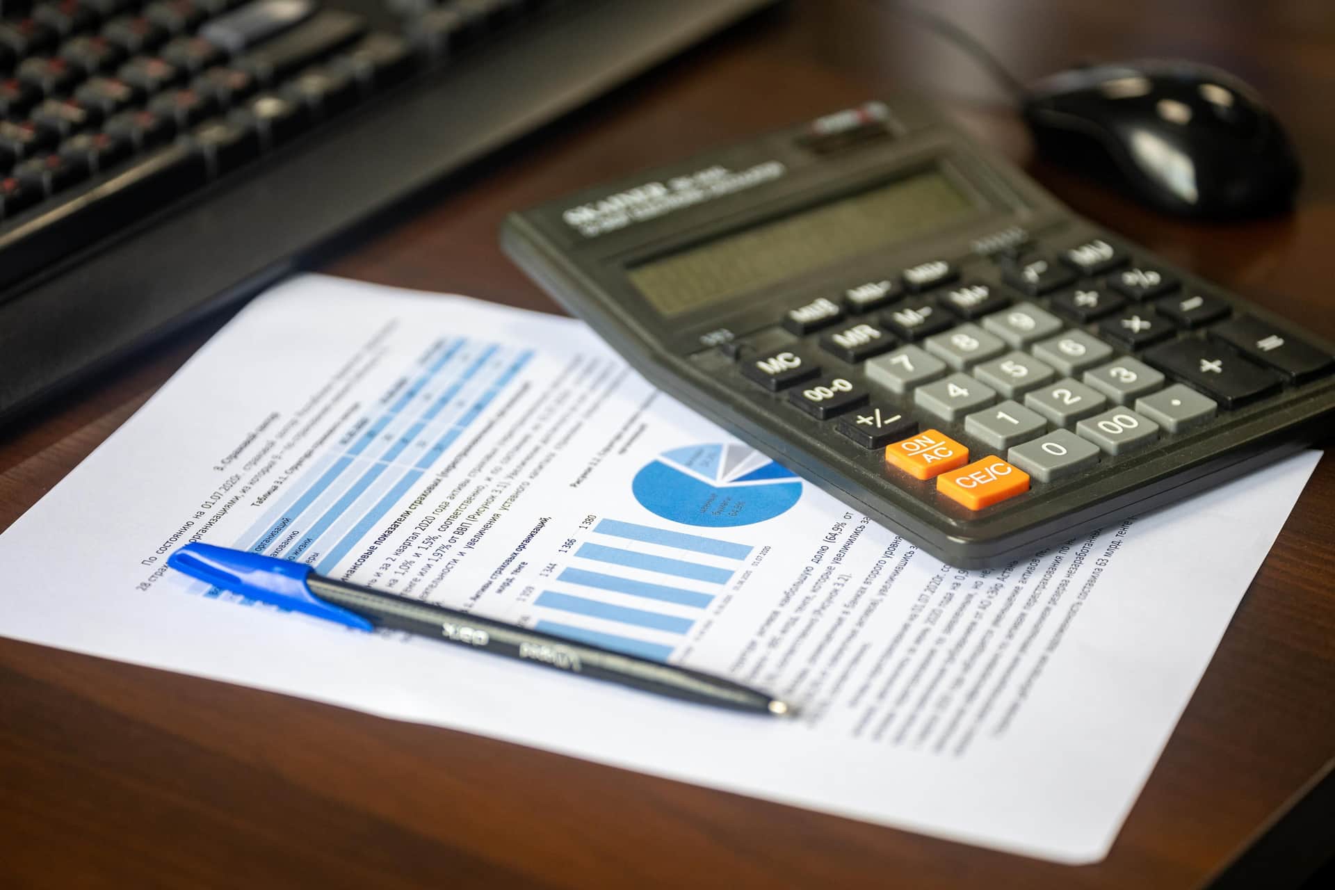 A calculator and a pen on a dark desk surface
