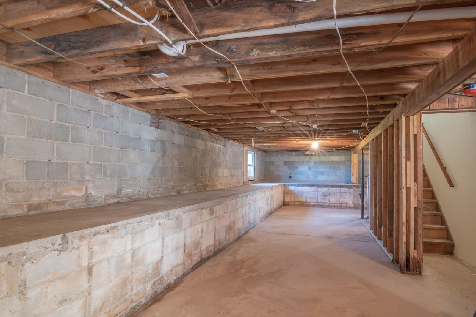 An unfinished basement wall of concrete block in hard directional light